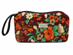 A rectangular zippered pouch with a wrist strap, featuring a vintage floral pattern in orange, beige, and green on a dark red background. A small white label on the front reads 'TRANSCEND Artisan Made'. 23