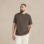 Man wearing a brown t-shirt and white pants against a beige background 10