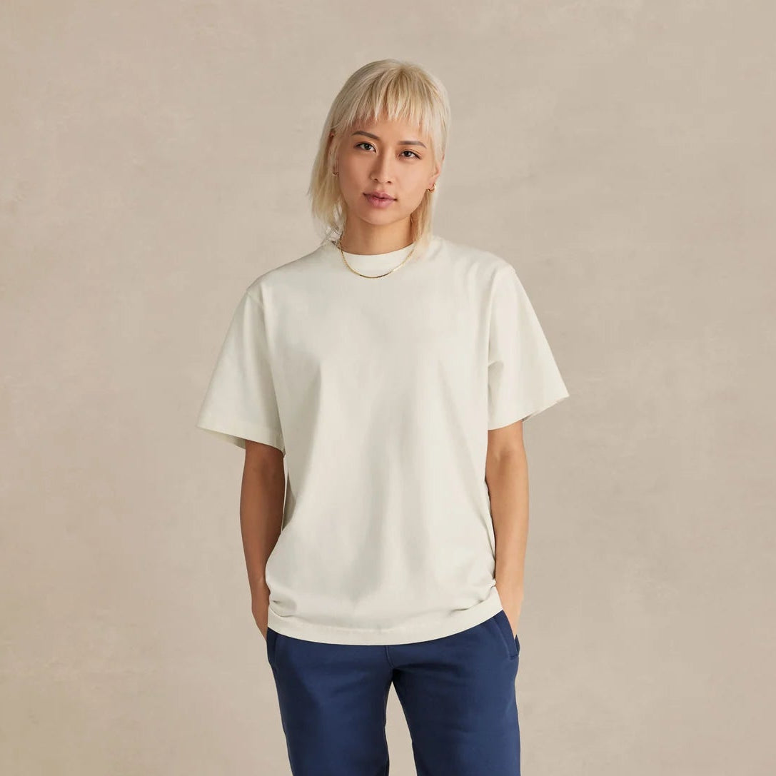 Person wearing a white t-shirt and blue pants on a beige background