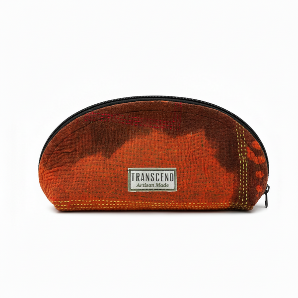 A translucent zippered pouch with a textured orange and brown pattern, featuring a white rectangular label that reads 'TRANSCEND Artisan Made'.