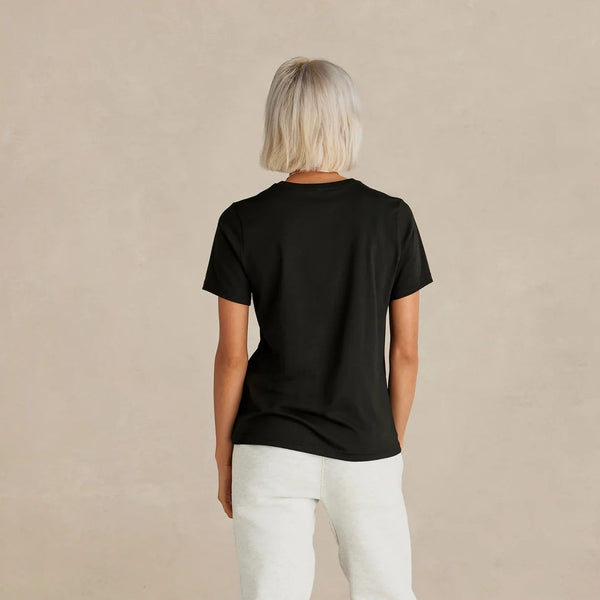 Person wearing a black t-shirt and white pants on a beige background