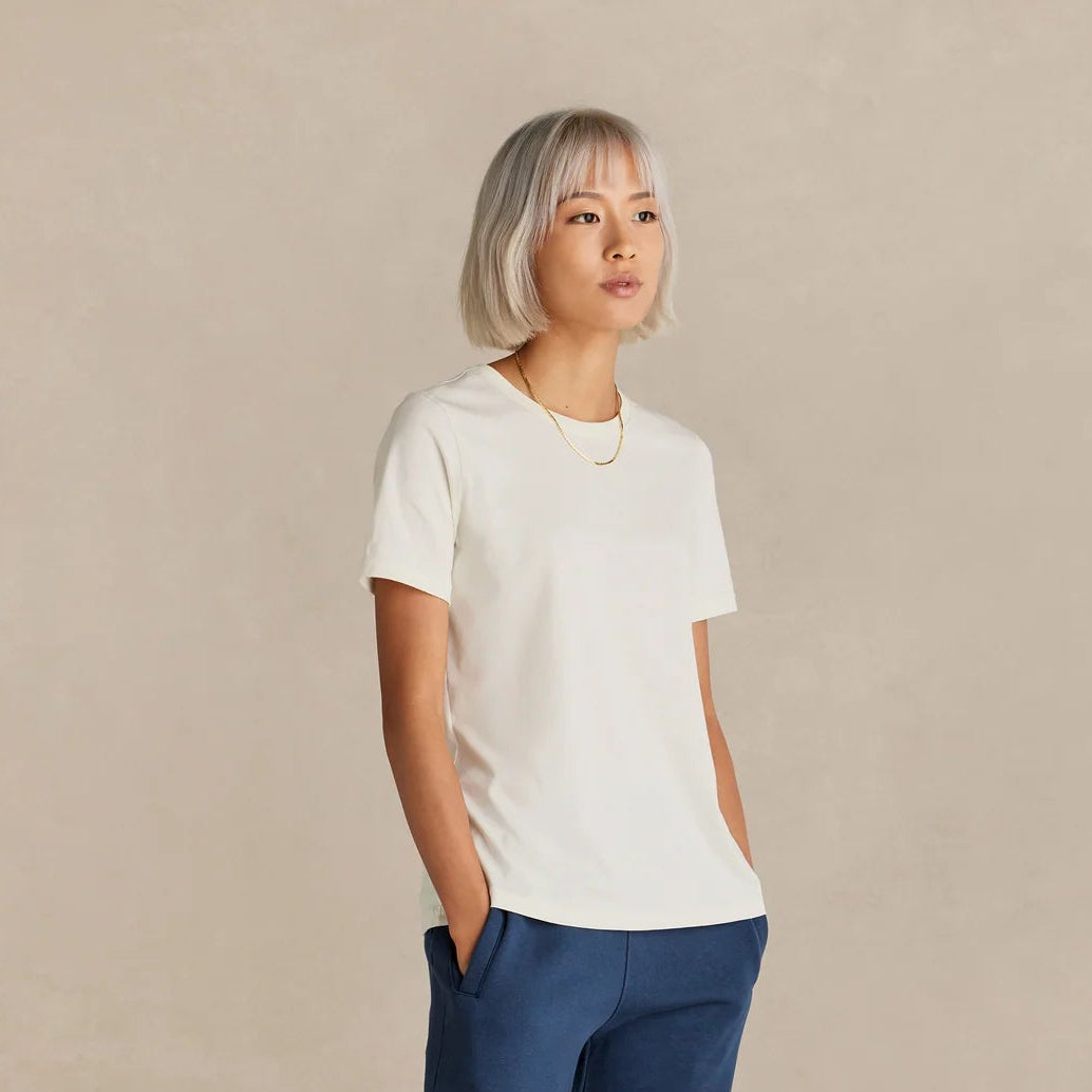 Person wearing a white t-shirt and blue pants on a beige background