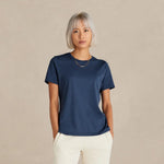 Person wearing a navy blue t-shirt and white pants on a beige background 11